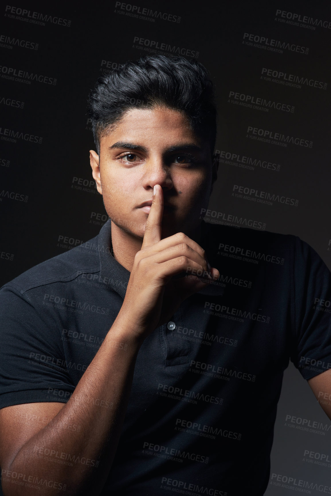 Buy stock photo Studio shot of a young man posing with his finger on his lips