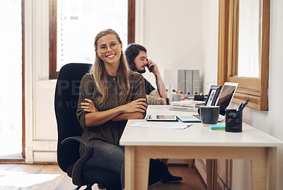 Buy stock photo Portrait of a confident young businesswoman working in an office with her colleague in the background