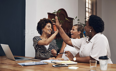 Buy stock photo Shot of a group of young businesswomen giving each other high five during a meeting in a modern office