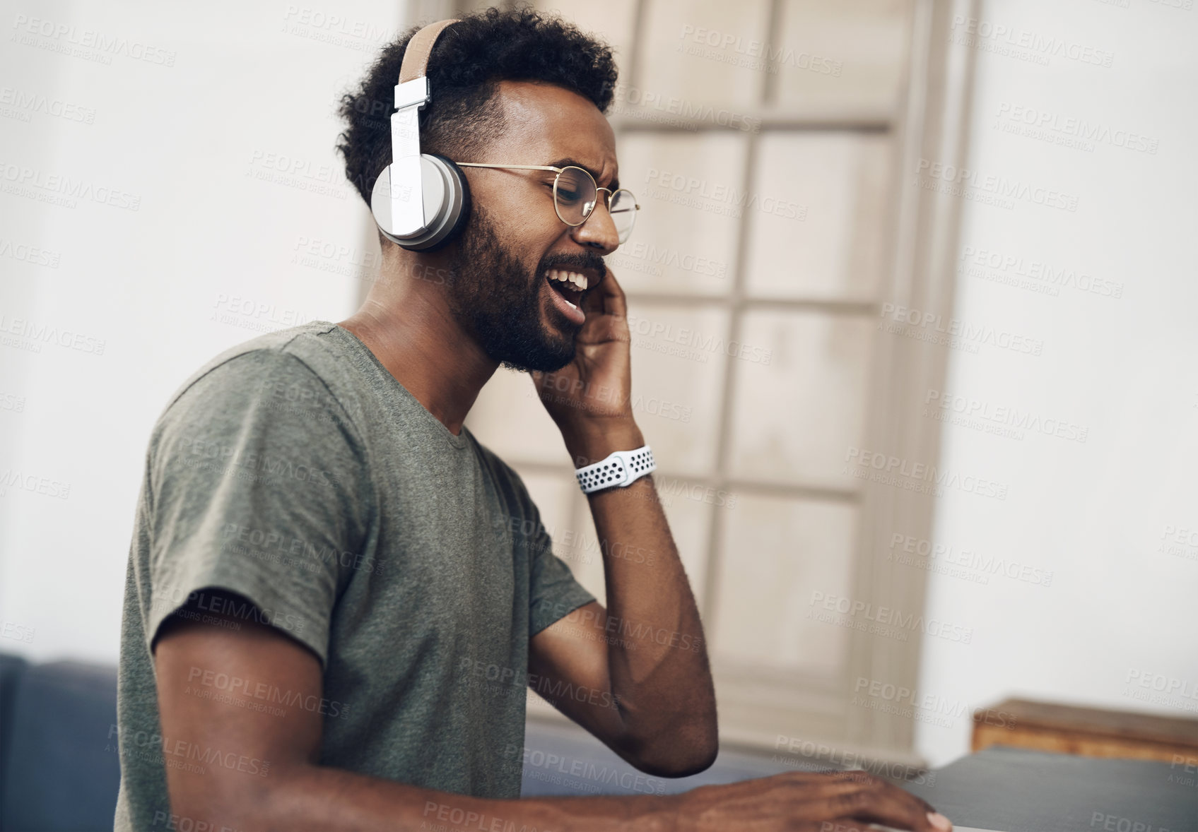 Buy stock photo Shot of a young businessman using headphones while working in a modern office