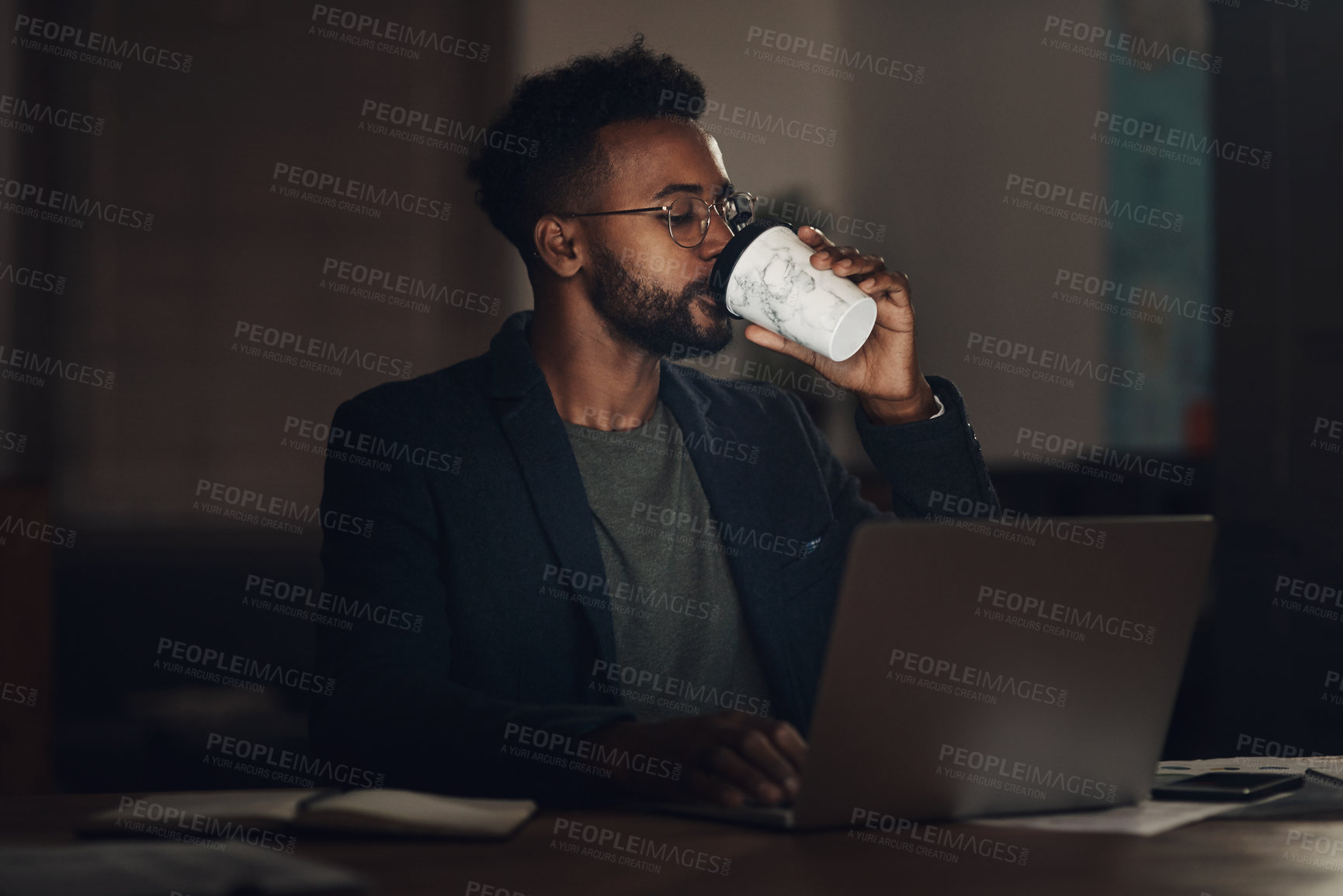 Buy stock photo Black man, laptop or night with coffee for deadline, project or design at office desk. Young African, male person or designer working late on computer with caffeine drink or beverage at workplace