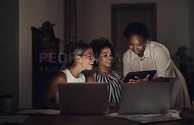 Buy stock photo Shot of a group of young businesswomen using a laptop and digital tablet during a late night at work