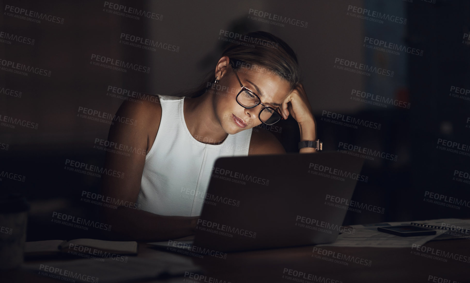Buy stock photo Shot of a young businesswoman looking worn out while using a laptop during a late night at work