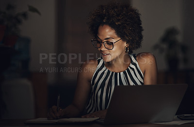 Buy stock photo Shot of a young businesswoman going over paperwork and using a laptop during a late night at work