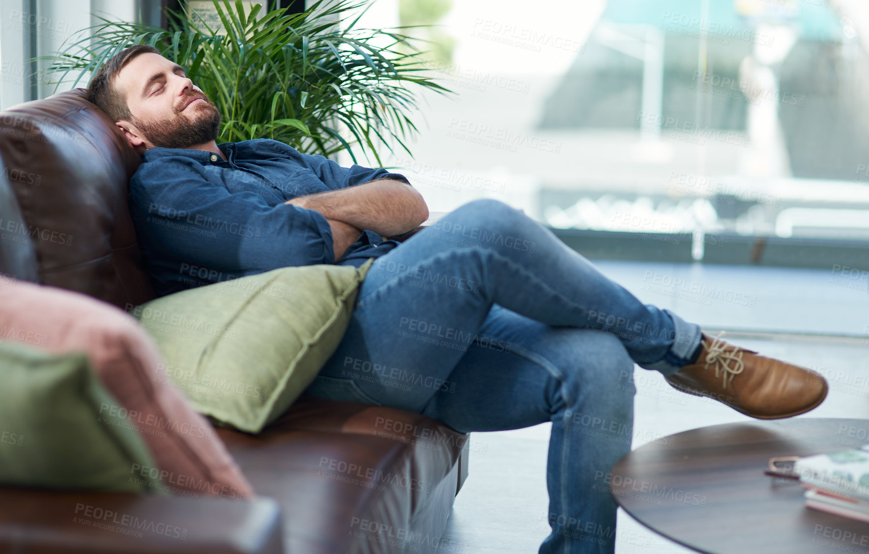 Buy stock photo Shot of a young man relaxing on a sofa