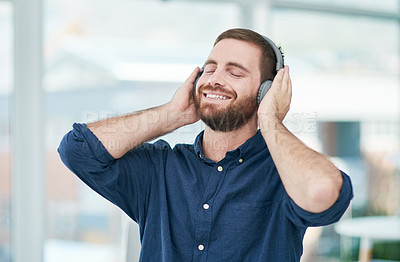 Buy stock photo Shot of a happy young businessman using headphones in a modern office
