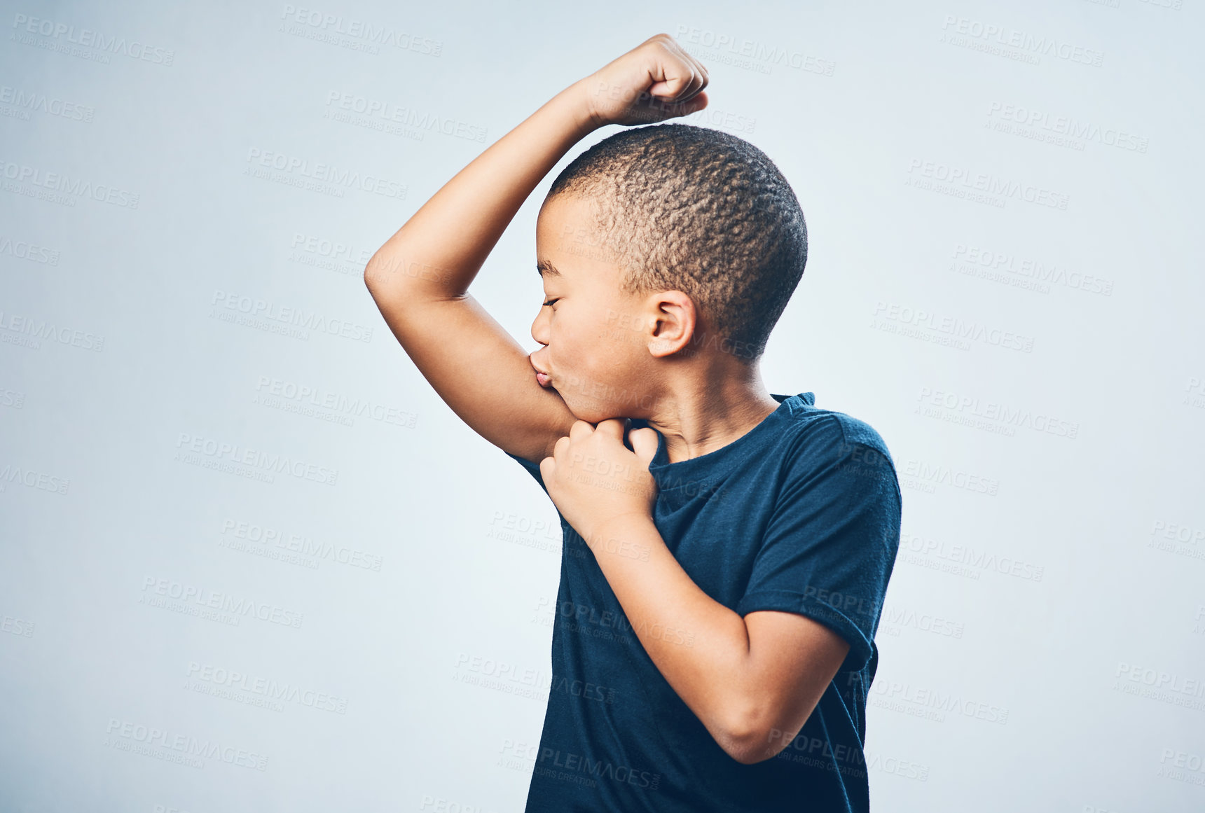 Buy stock photo Studio shot of a cute little boy kissing his muscles against a grey background