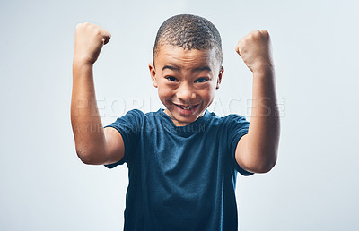 Buy stock photo Studio shot of a cute little boy flexing his muscles against a grey background
