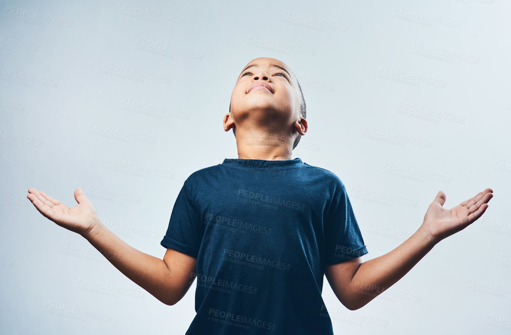 Buy stock photo Studio shot of a cute little boy opening his arms and looking up against a grey background