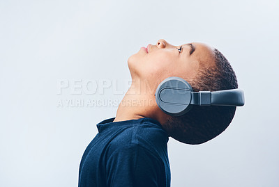 Buy stock photo Boy, child and headphones in studio, thinking and listening to podcast on white background. Male person, profile and tech connection for hearing audio or inspiration, streaming radio and playlist