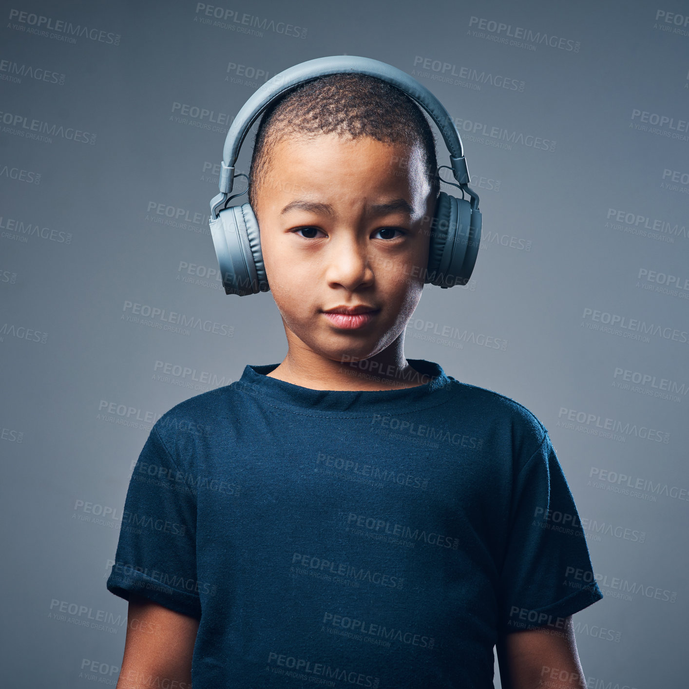 Buy stock photo Portrait, boy and serious with headphones in studio for streaming music, audio and radio in Brazil. Male person, kid and confidence with headset on gray background for playlist, song and album