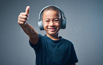 Buy stock photo Studio shot of a cute little boy using headphones and showing thumbs up against a grey background