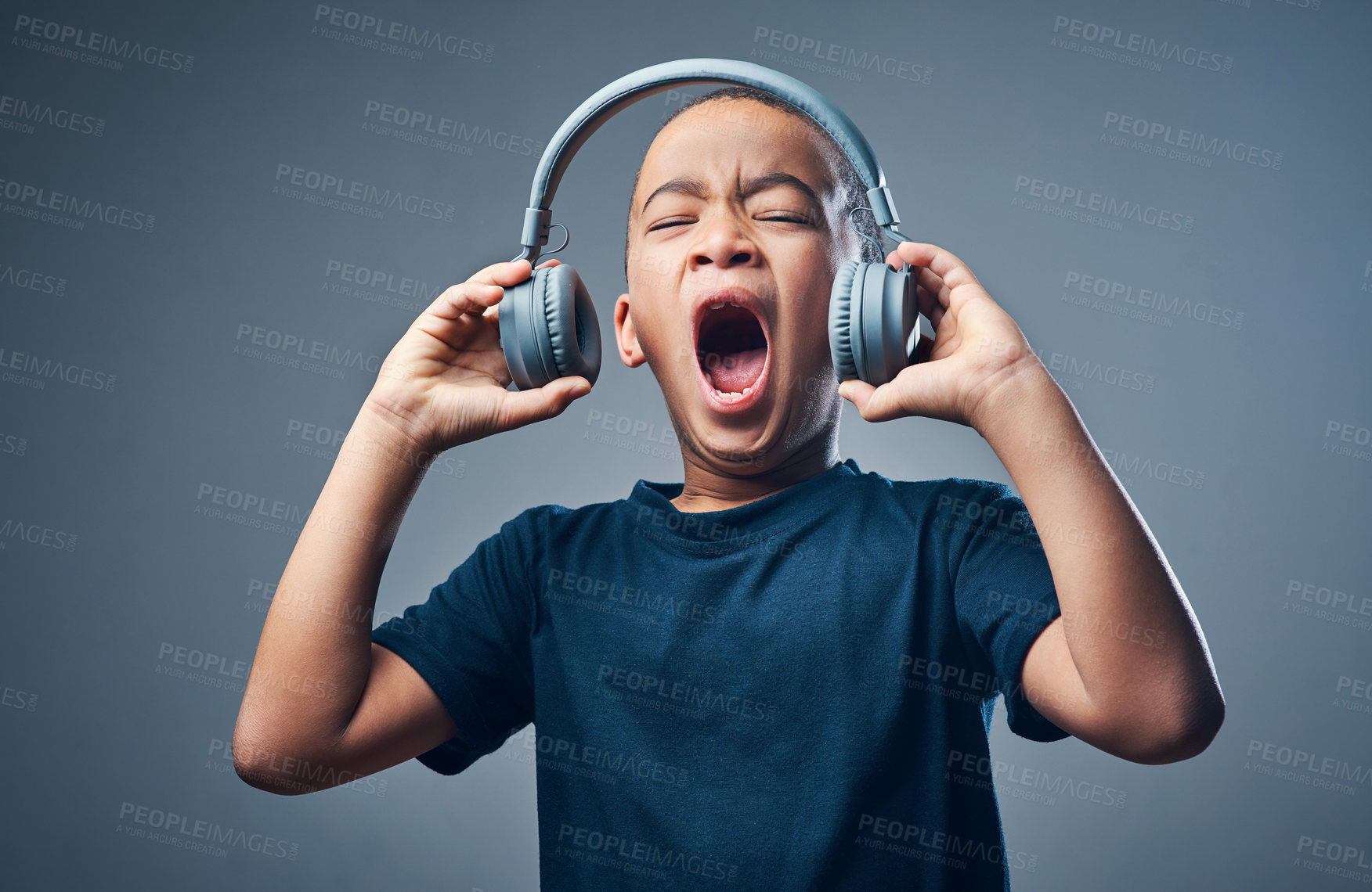Buy stock photo Studio shot of a cute little boy using headphones with his mouth open against a grey background