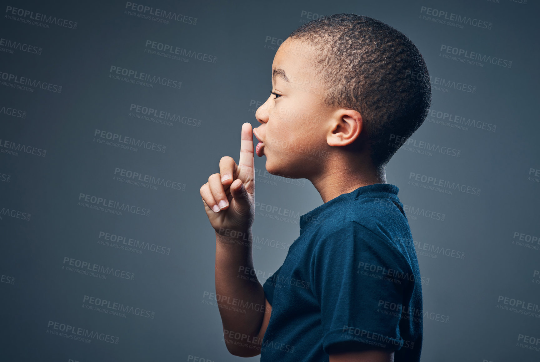 Buy stock photo Studio shot of a cute little boy posing with his finger on his lips against a grey background