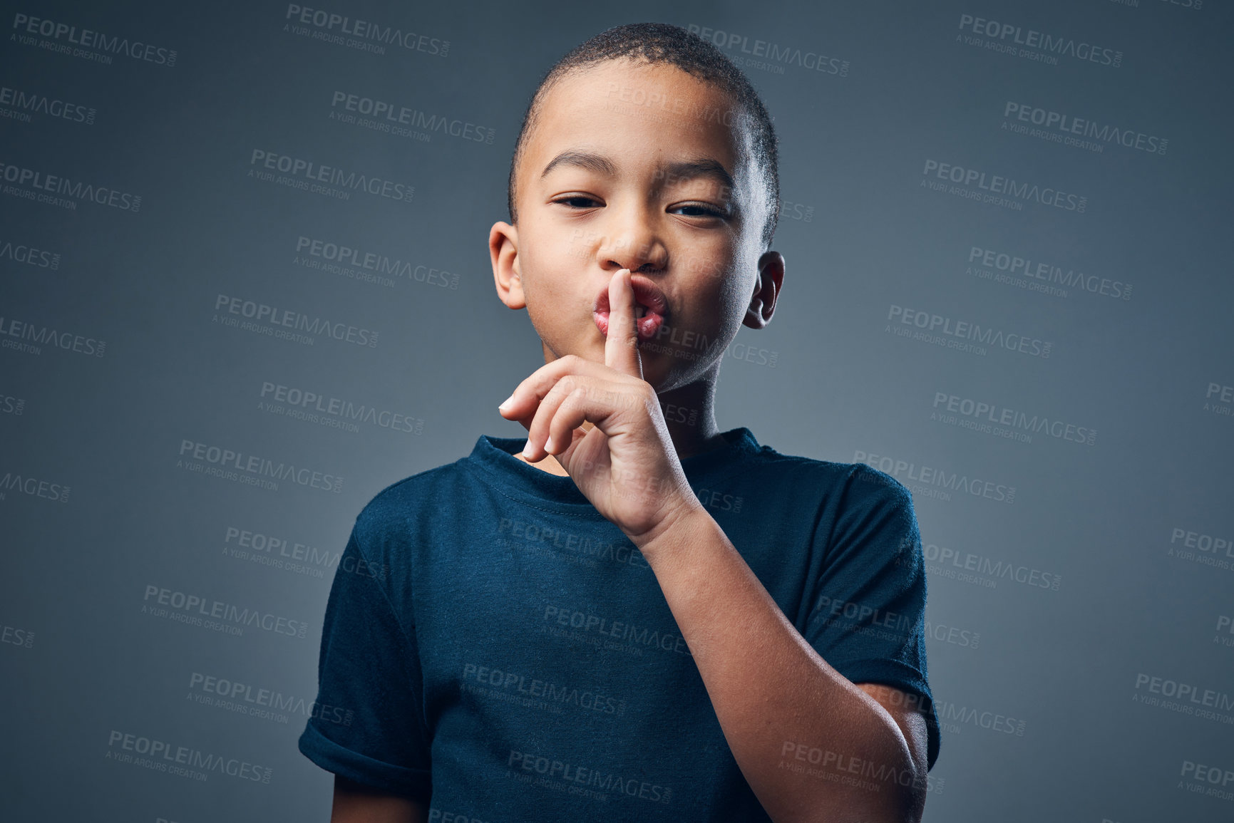 Buy stock photo Studio shot of a cute little boy posing with his finger on his lips against a grey background