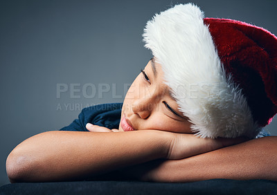 Buy stock photo Studio shot of a cute little boy wearing a Santa hat and looking thoughtful against a grey background