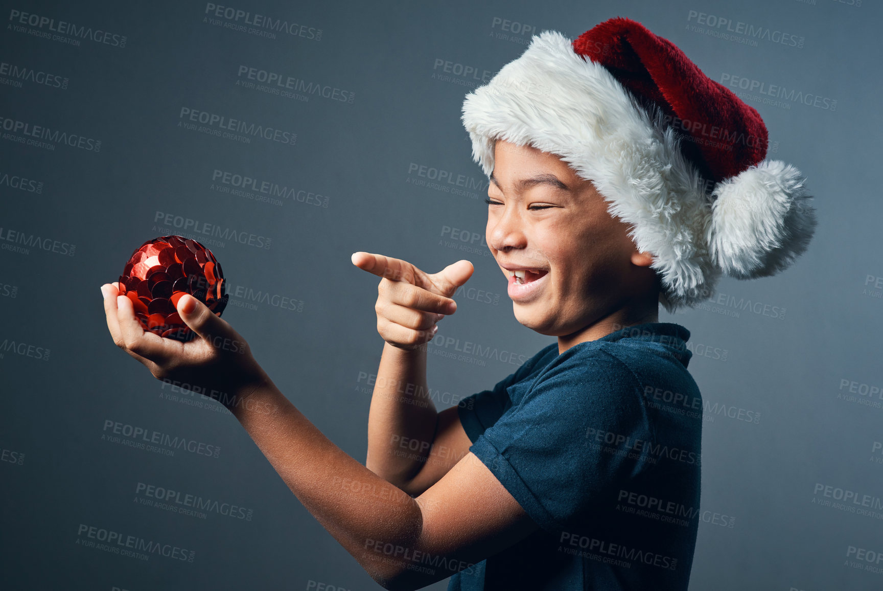 Buy stock photo Studio shot of a cute little boy playing with a Christmas decoration against a grey background