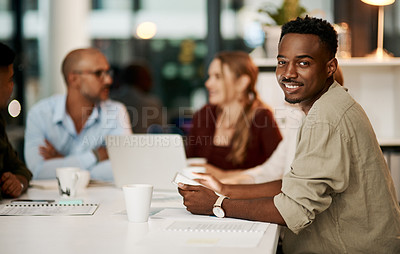 Buy stock photo Proud, happy and smiling young businessman holding digital tablet during business meeting. Ambitious young businessperson with team or colleagues in office, sitting in a modern boardroom.