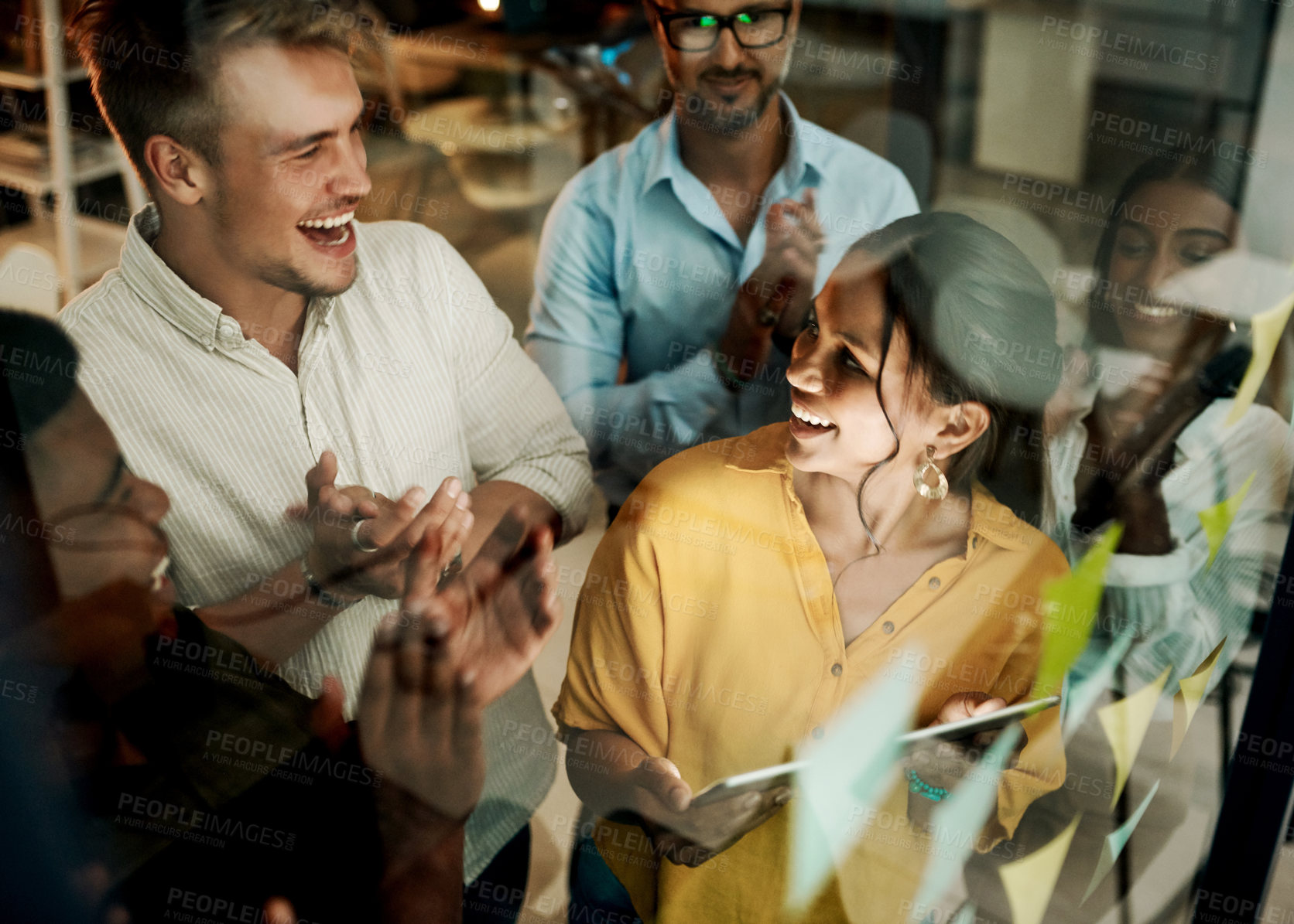 Buy stock photo Successful business team clapping and cheering after planning a project on a glass wall in a office. Group of smiling businesspeople sharing ideas and strategies together in a creative startup agency