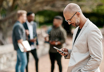 Buy stock photo Shot of a mature businessman using a smartphone against a city background