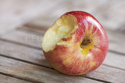 Buy stock photo Closeup of bitten red apple eaten as healthy diet or snack for nutrition and vitamins. Detail texture of sweet, tasty or fresh fruit isolated on wood background with copy space on sustainable orchard