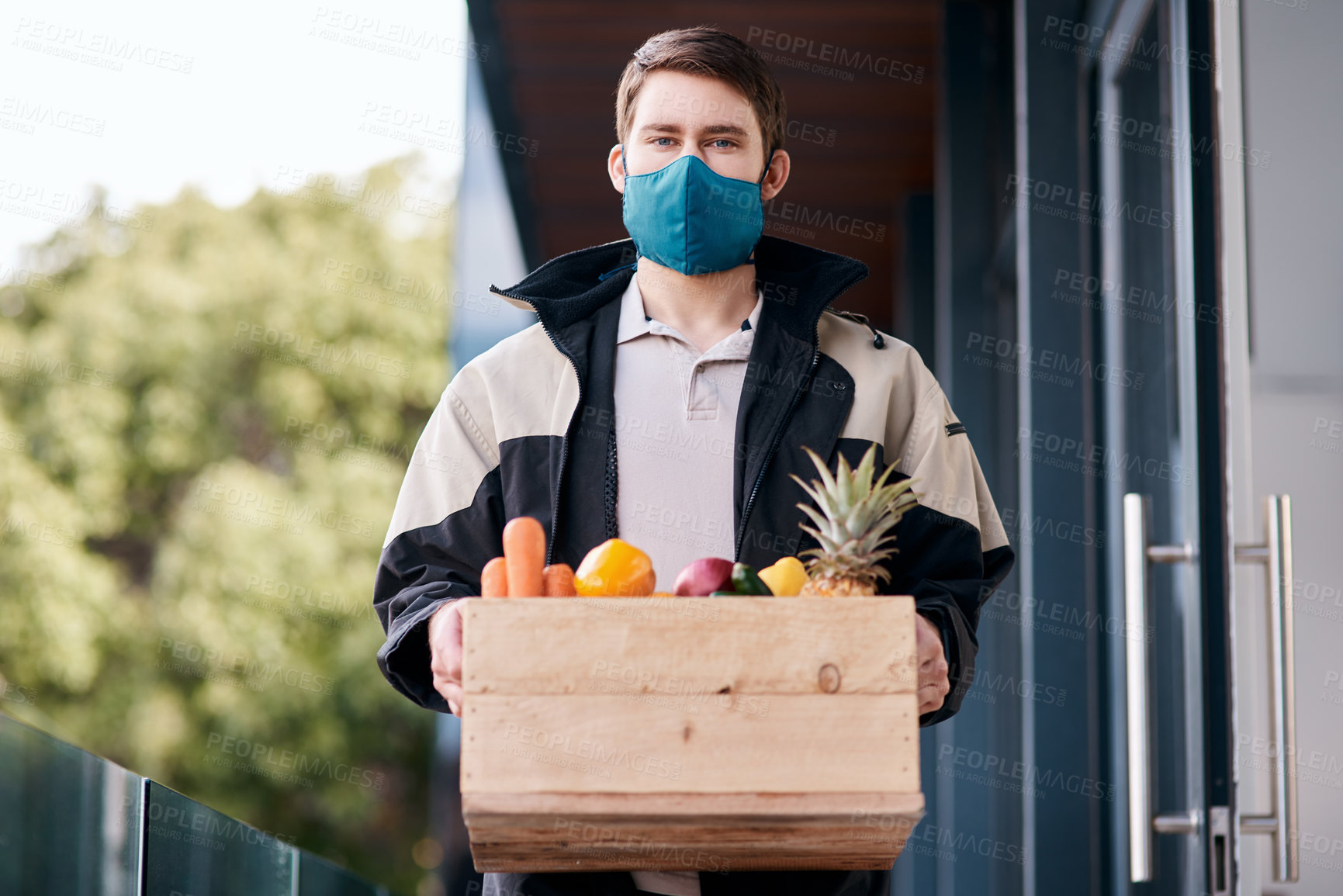 Buy stock photo Shot of a masked young man delivering fresh fruit and vegetables to a place of residence