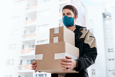 Buy stock photo Shot of a masked young man delivering delivering a package to a place of residence