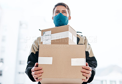Buy stock photo Shot of a masked young man delivering delivering a package to a place of residence