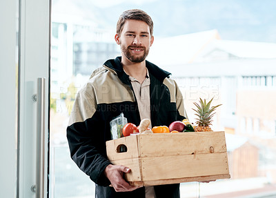Buy stock photo Shot of a young man delivering fresh fruit and vegetables to a place of residence