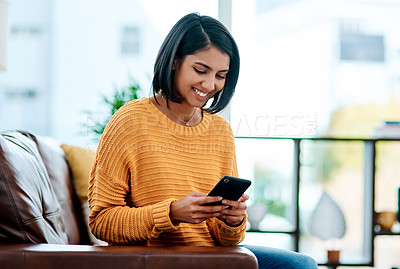 Buy stock photo Shot of a young woman using a smartphone on the sofa at home