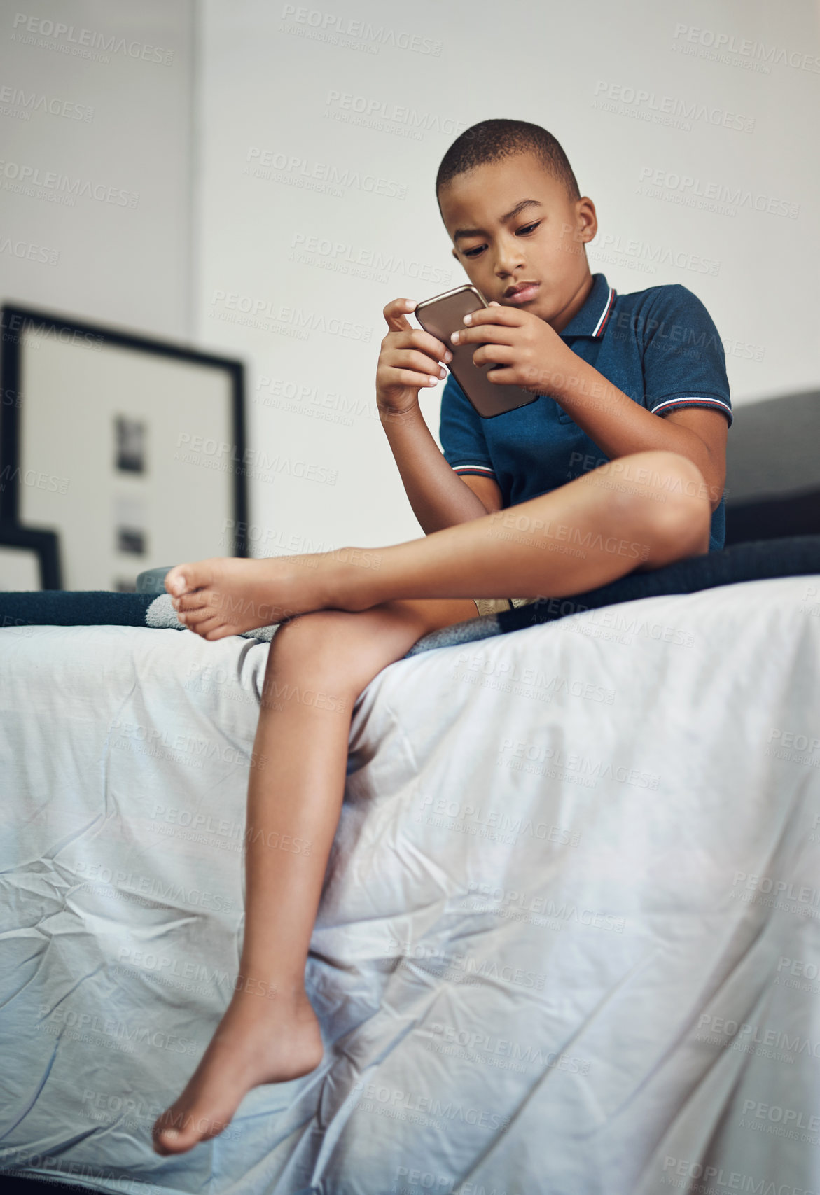 Buy stock photo African boy, smartphone and browse on bed for education, app or streaming subscription with movie or video. Child, cellphone and learning in bedroom with remote schooling, show or cartoon in home