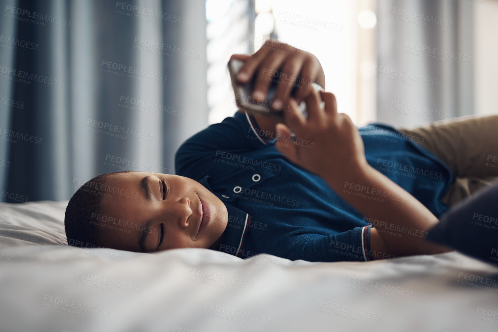 Buy stock photo African boy, smartphone and smile on bed for education, app or streaming subscription with movie or video. Child, cellphone and learning in bedroom with remote schooling, show or cartoon in home