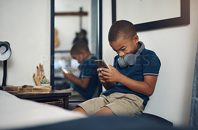 Buy stock photo Shot of a young boy using a cellphone while sitting at home
