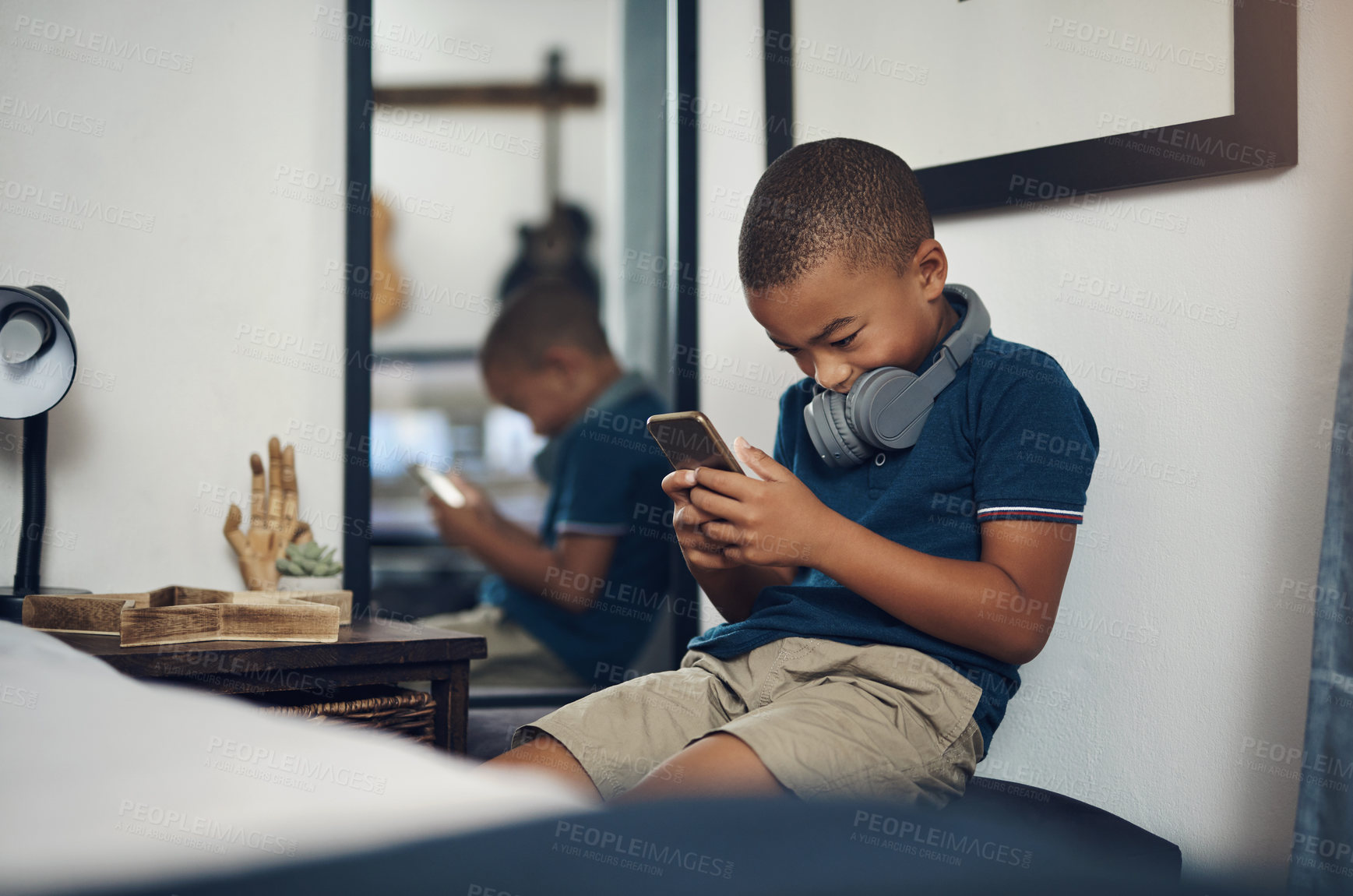 Buy stock photo Shot of a young boy using a cellphone while sitting at home