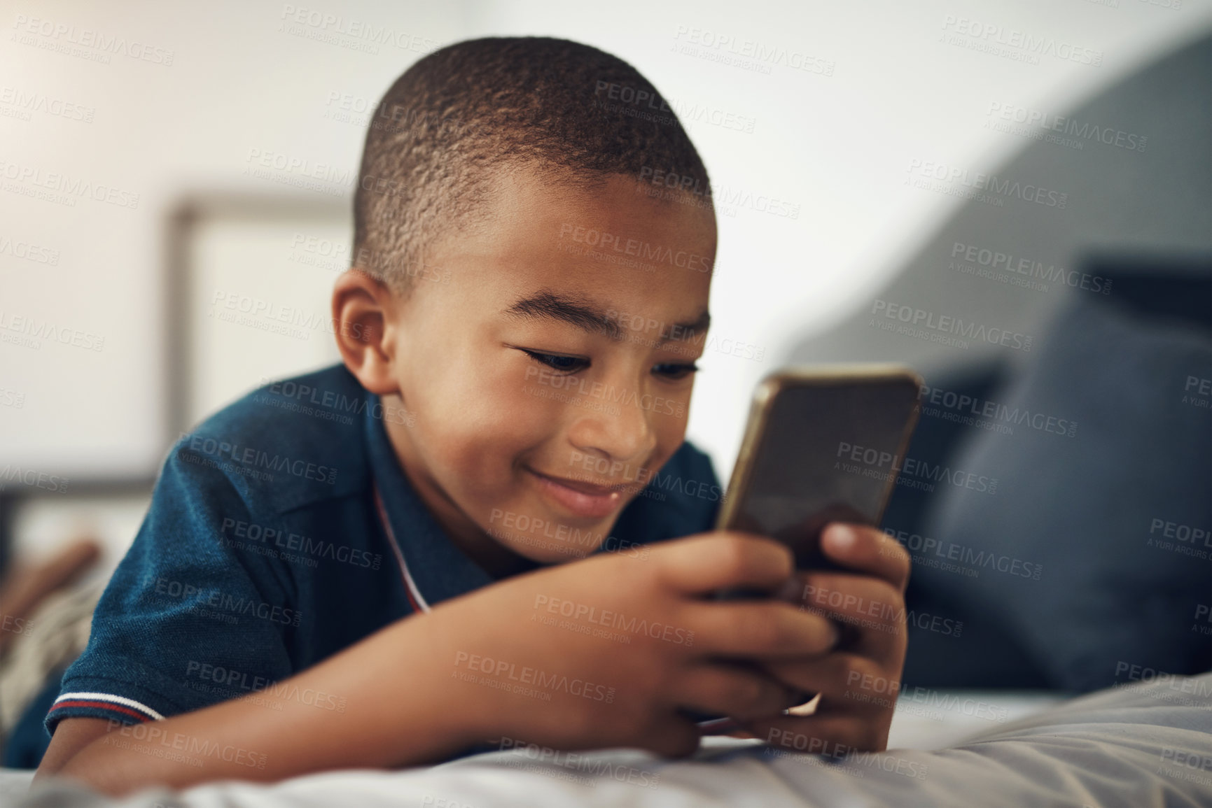 Buy stock photo African boy, smartphone and search in bedroom for smile, social media app or streaming subscription with movie or video. Child, cellphone and fun on bed with mobile gaming, show or cartoon in home