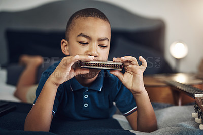 Buy stock photo Cropped shot of a young boy playing the harmonica at home