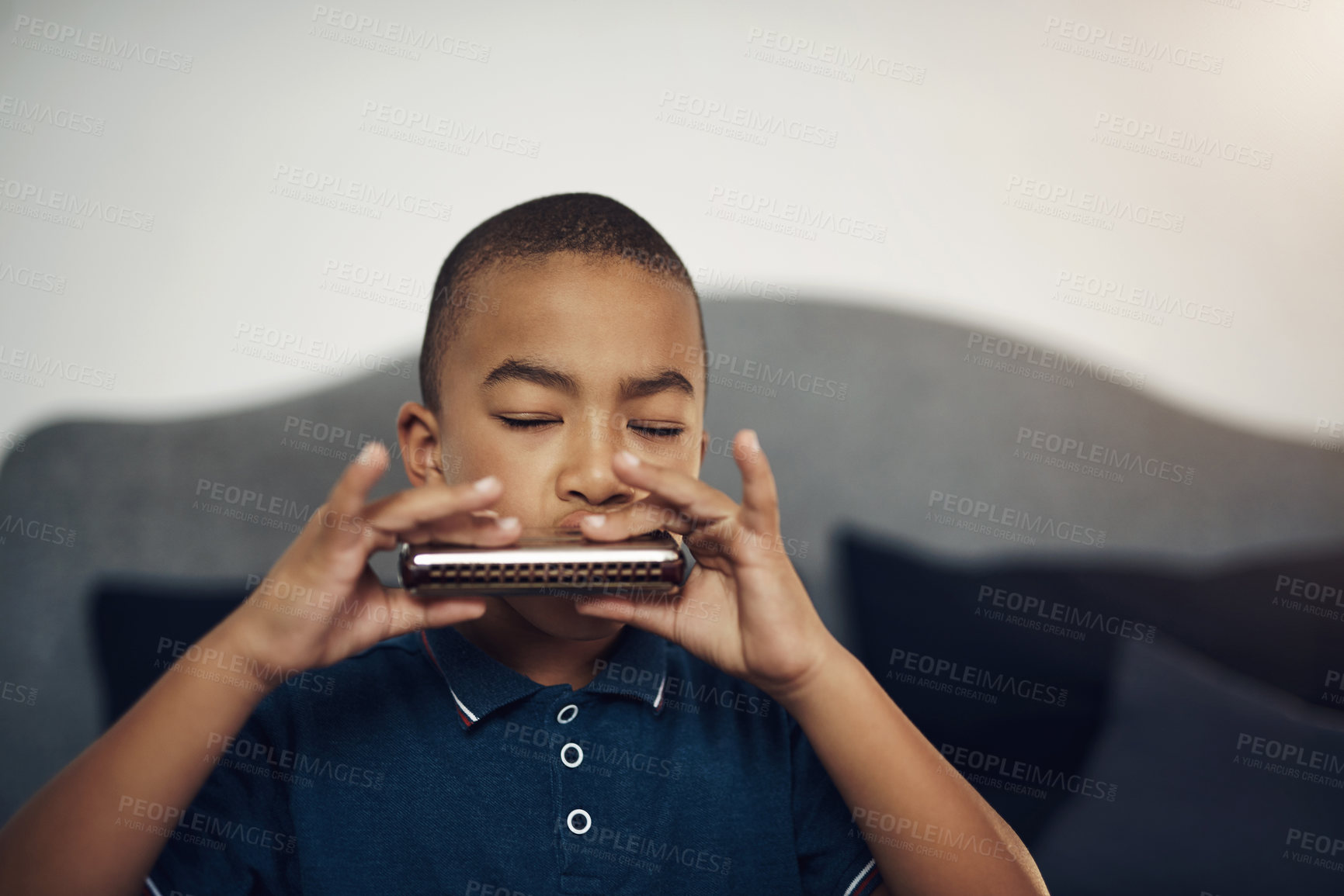 Buy stock photo Cropped shot of a young boy playing the harmonica at home