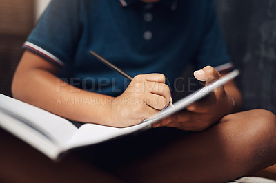 Buy stock photo Cropped shot of an unrecognizable boy writing in a book at home