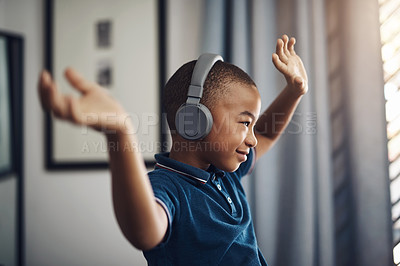 Buy stock photo Shot of a young boy listening to music through headphones while sitting at home
