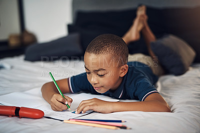 Buy stock photo Shot of a young boy using colouring pencils while writing at home