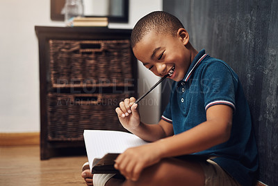 Buy stock photo Shot of a young boy writing in a book while sitting at home