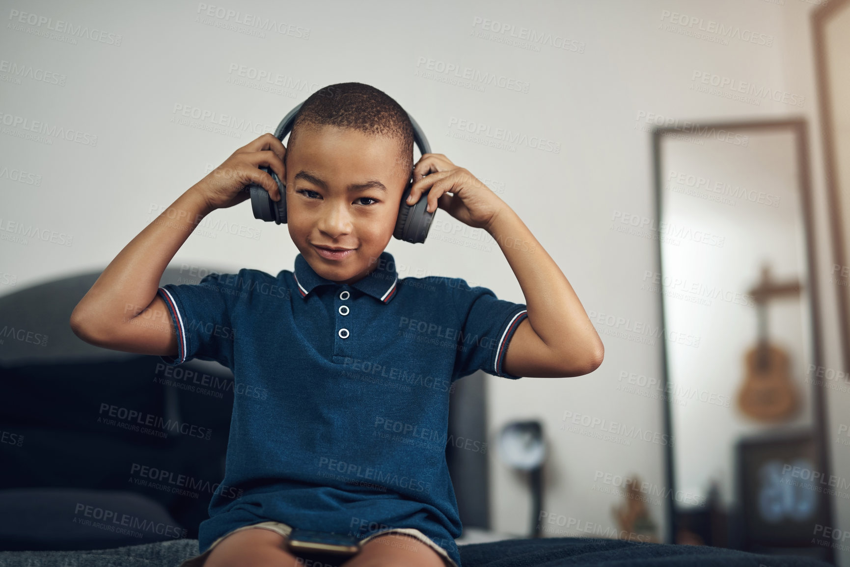 Buy stock photo Shot of a young boy listening to music through headphones while sitting at home