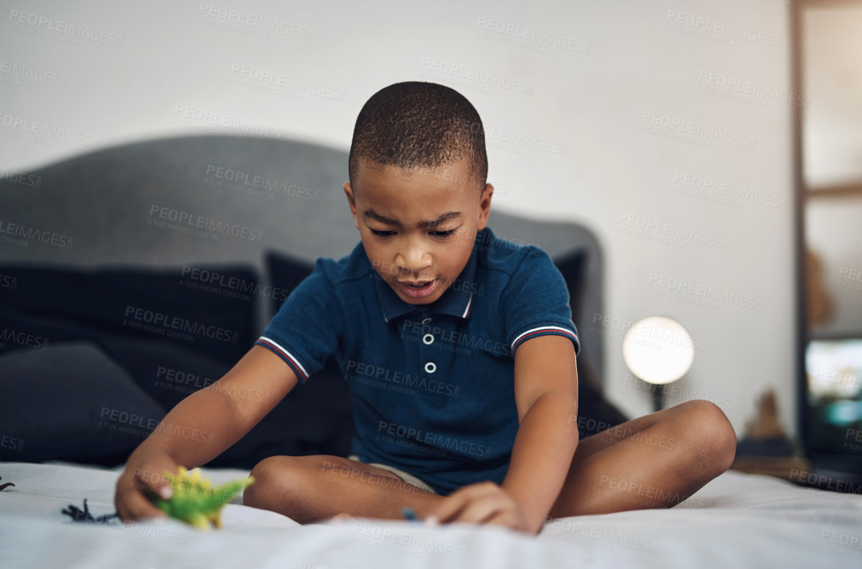 Buy stock photo Boy, playing and bed with dinosaur toys for fun entertainment, game or childhood at home. Young, male person or teenager with small action figures, imagination or fossil creatures in bedroom at house