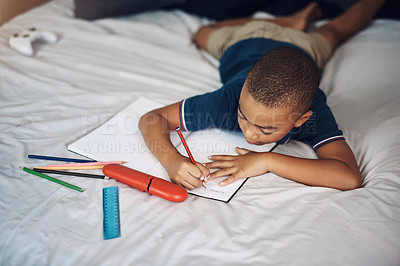 Buy stock photo Shot of a young boy using a pencil while writing at home