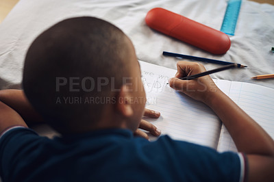 Buy stock photo Boy, lying and writing with book in bedroom for creativity, literature or drawing for educational activity at home. Young, male person or child sketching with coloring pencils for homework in bed