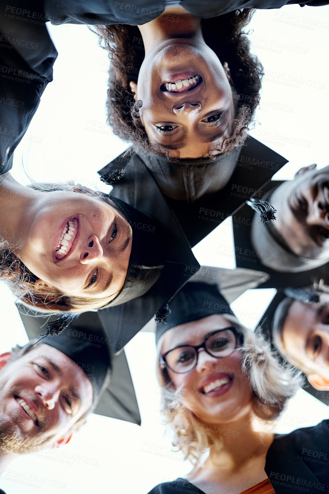 Buy stock photo Portrait of a group of students putting their heads together in a huddle on graduation day