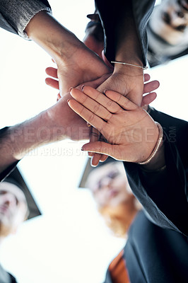 Buy stock photo Low angle shot of a group of students holding their hands together in a huddle on graduation day