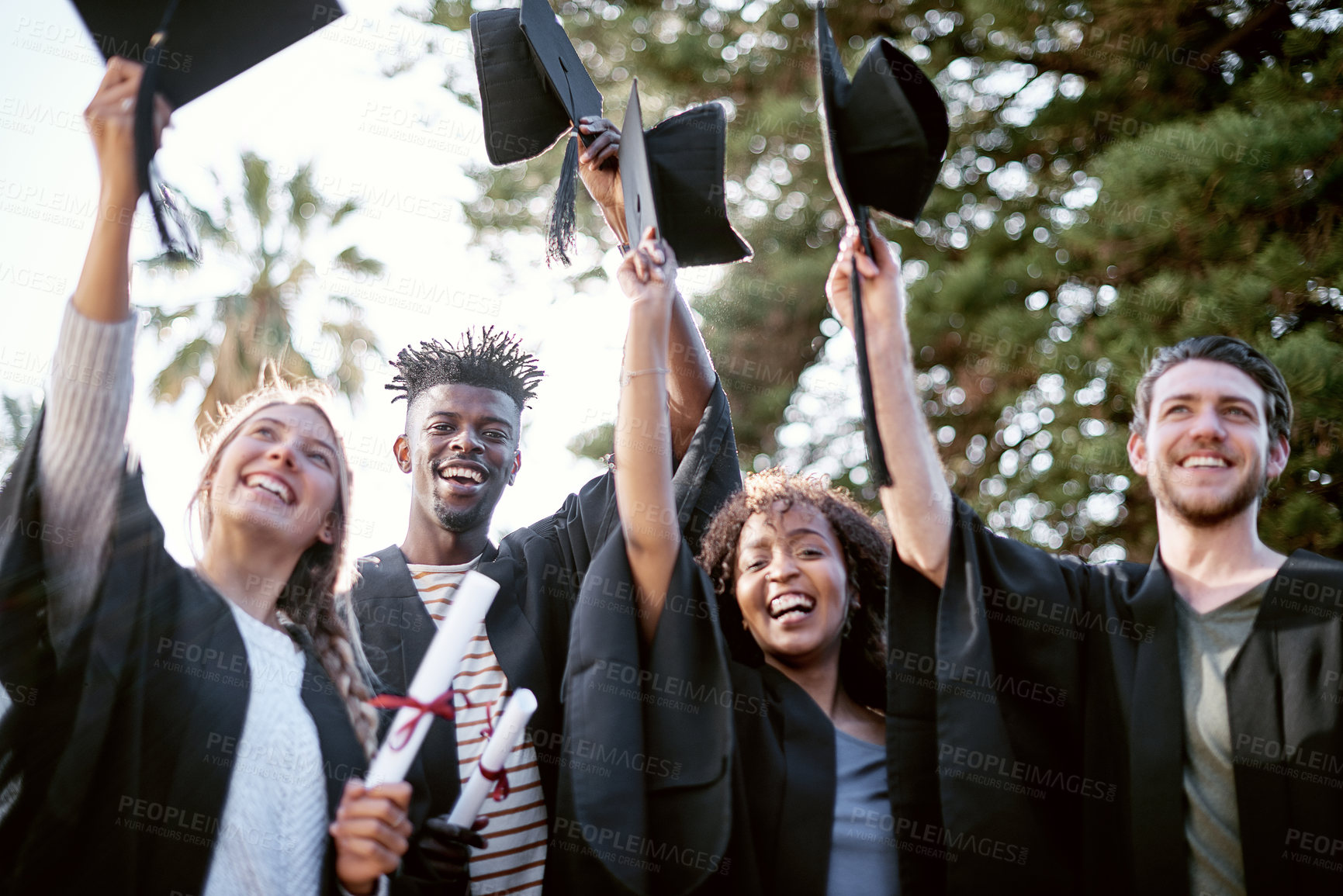 Buy stock photo Portrait of a group of students holding raising hats in celebration on graduation day