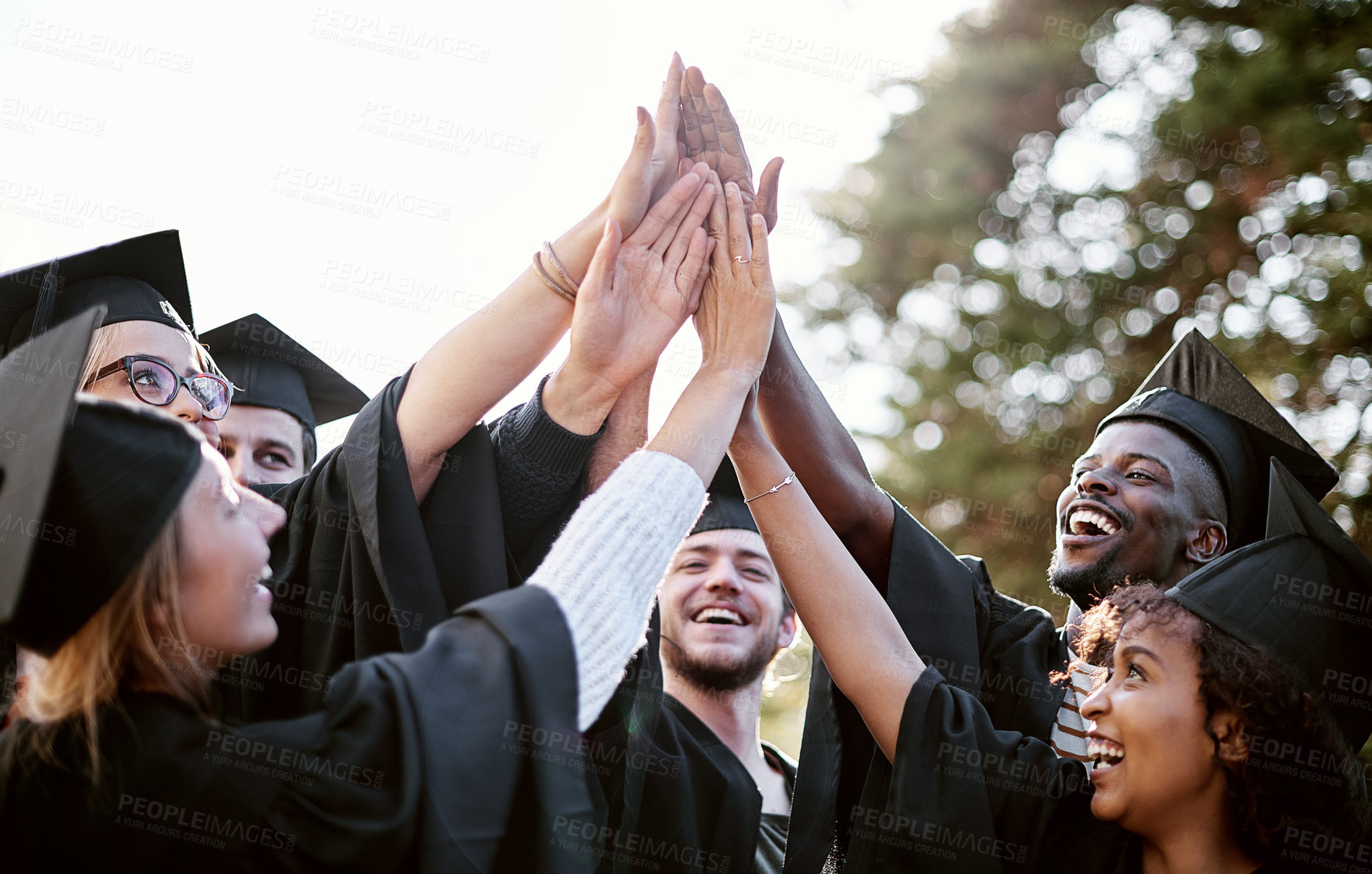 Buy stock photo Shot of a group of students giving each other a high five on graduation day