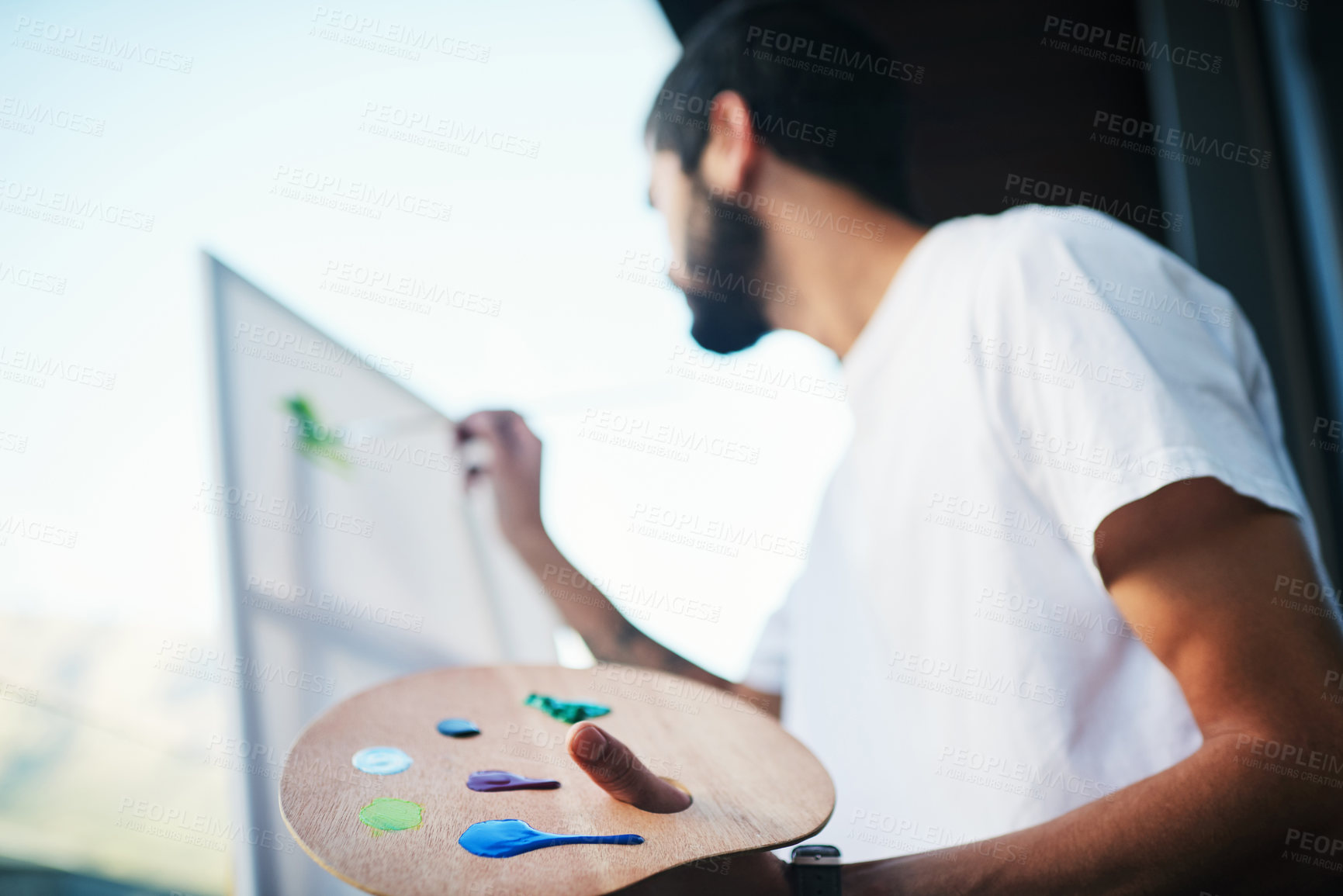 Buy stock photo Cropped shot of a man painting on a canvas while sitting on the balcony at home